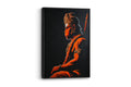 A framed vertical canvas art print depicting Hanuman in profile, illuminated in glowing orange-red tones against a dark background, shown hanging on a light gray wall.