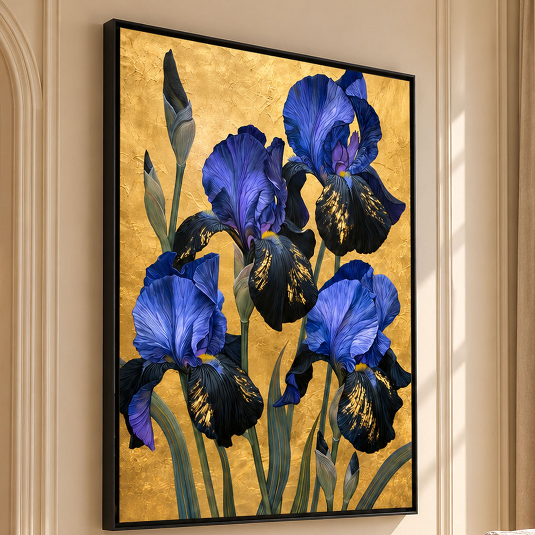 A framed canvas wall art print featuring blue irises on a textured gold background, displayed in a real living room setting with beige walls, a window, curtains, and a sofa.