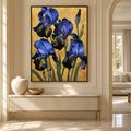 A framed wall art print featuring large blue and black irises on a textured gold background, displayed in a beige interior hallway above a console table.