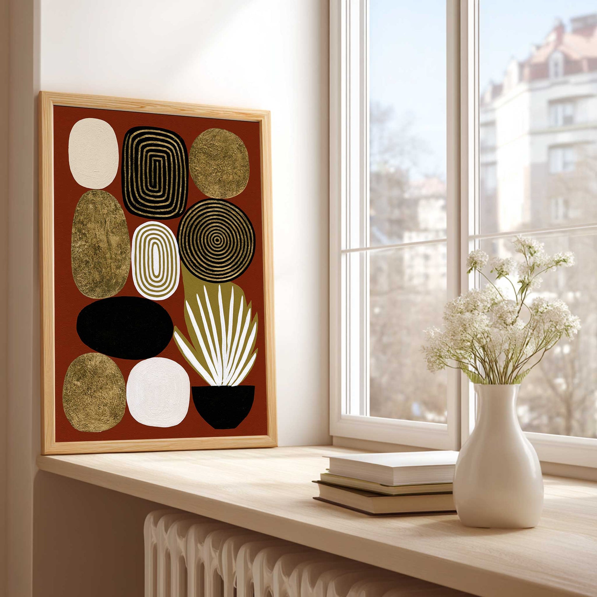 Mid century modern boho abstract art print featuring a collection of stacked geometric pebble shapes on a rust terracotta background. Designs include gold foil textured stones, black concentric circles, concentric white and gold rings, and a potted white spike plant in a black bowl