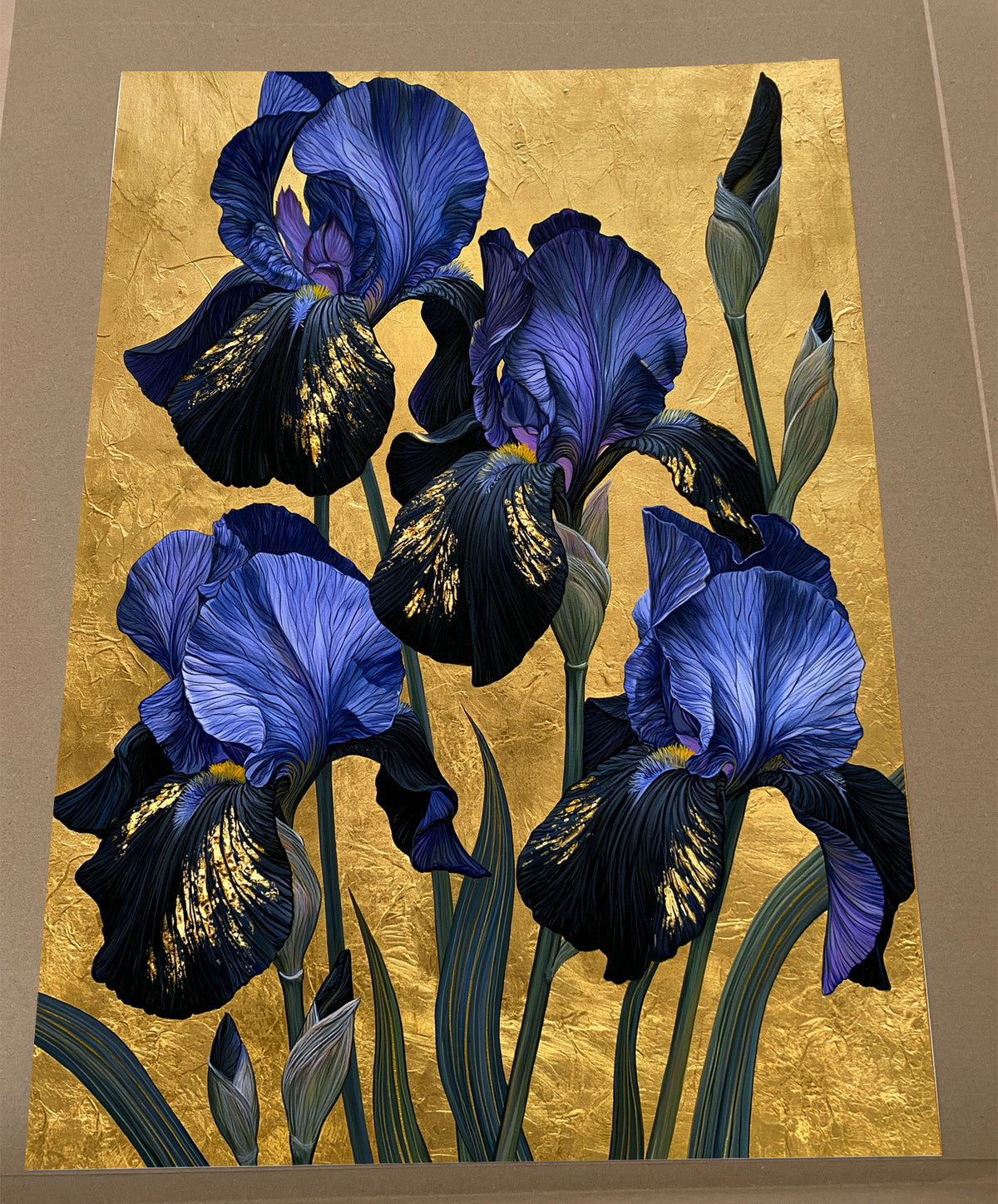 Blue iris wall art print featuring blue and violet iris flowers with green leaves on a rich gold-coloured background.
